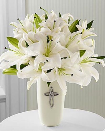 This striking display of pure white lilies will send your heartfelt expressions when words just aren't enough. Arranged in a white ceramic vase and enhanced by a cross, this arrangement is perfect for celebrations, confirmations, sympathy, weddings, or a special anniversary.This is an all-around arrangement.