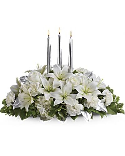 <p>Blanket your holiday table in elegance with this lush white floral Christmas centerpiece. Beautiful white hydrangeas and lilies form a snow white cloud beneath three slender silver candles.<br />
White flowers, including hydrangeas, asiatic lilies and carnations - are combined with deep green salal, variegated pittosporum and silver leaves beneath three silver taper candles.</p>