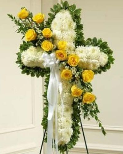 <p>Send a beautiful floral tribute that expresses the love and sympathy you feel during this difficult time. This standing spray arrangement in the shape of a cross is created from fresh yellow and white flowers such as roses, football mums and more. Traditionally sent directly to the funeral home by family members or friends and displayed on a stand.</p>