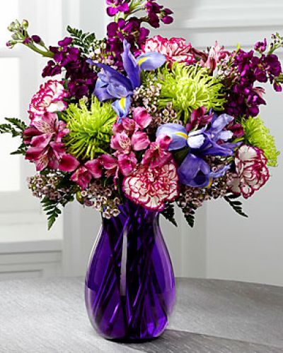 <p>Blooming with rich color and undeniable texture, this stunning bouquet expresses love and gratitude with each perfect flower. Blue Iris, fragrant purple gilly flower, purple Peruvian Lilies, purple bi-color carnations, green spider chrysanthemums, clusters of pink wax flower, and lush greens create a fascinating display presented in a deep purple glass vase with modern lines to create a sophisticated look.</p>
