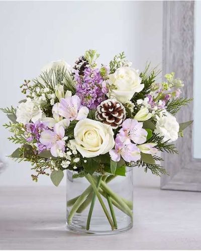 <p>We’ve captured the peaceful beauty of winter in our lovely bouquet. A new seasonal version of our best seller, it’s loosely gathered with soothing lavender & white blooms, cascading greenery all around and pinecone accents for a rustic touch. A truly wonderful way to express your sentiments this time of year.</p>
<ul>
<li>All-around arrangement with white roses and carnations; lavender Peruvian lilies (alstroemeria) and stock; accented with baby’s breath, seeded eucalyptus, pinecone picks and assorted Christmas greenery</li>
<li>Artistically designed a clear glass cylinder vase</li>
<li>Large arrangement measures approximately 15"H x 13"W</li>
<li>Medium arrangement measures approximately 13"H x 12"W</li>
<li>Small arrangement measures approximately 12"H x 9"W</li>
<li>Our florists select the freshest flowers available, so colors, varieties and container may vary due to local availability</li>
<li>To ensure lasting beauty, Peruvian lilies may arrive in bud form and will fully bloom over the next few days</li>
</ul>