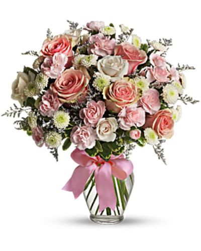 <p>Pretty pink roses, spray roses and miniature carnations, white button spray chrysanthemums, lavender limonium and green pittosporum fill a spring glass vase that's wrapped with a pink satin ribbon. It's confection perfection!</p>
